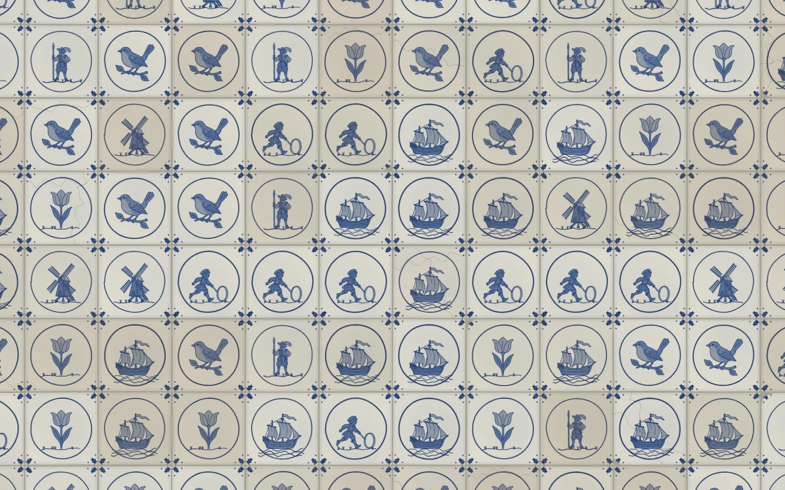 A wall of Delft tiles, each a small cobalt figure in a roundel on greyish white: ships under sail, birds on branches, windmills, tulips, pikemen with their pikes and children running with hoops, with small ox-head motifs in the corners between tiles