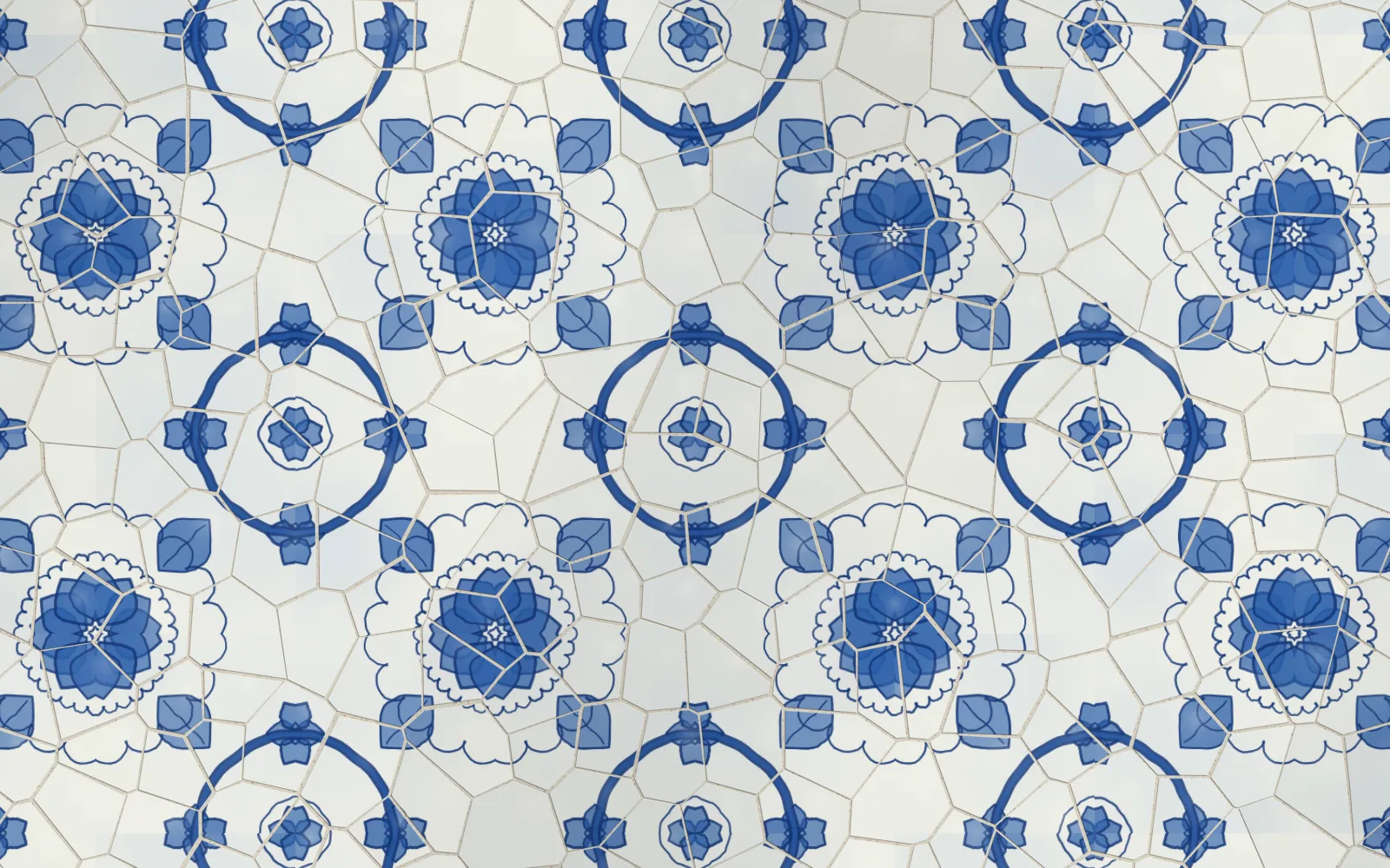 A close view of a cobalt and white painted tile wall of rosettes and rings, cracked into shards with fine lime joints, the pattern whole across the cracks